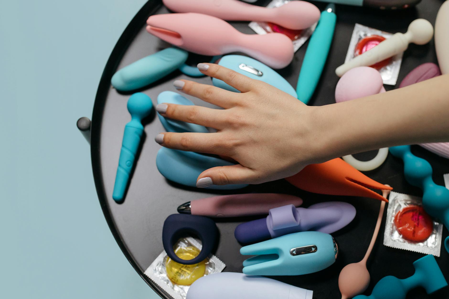 A woman holds two colorful vibrators against a purple background, representing choice and pleasure options.