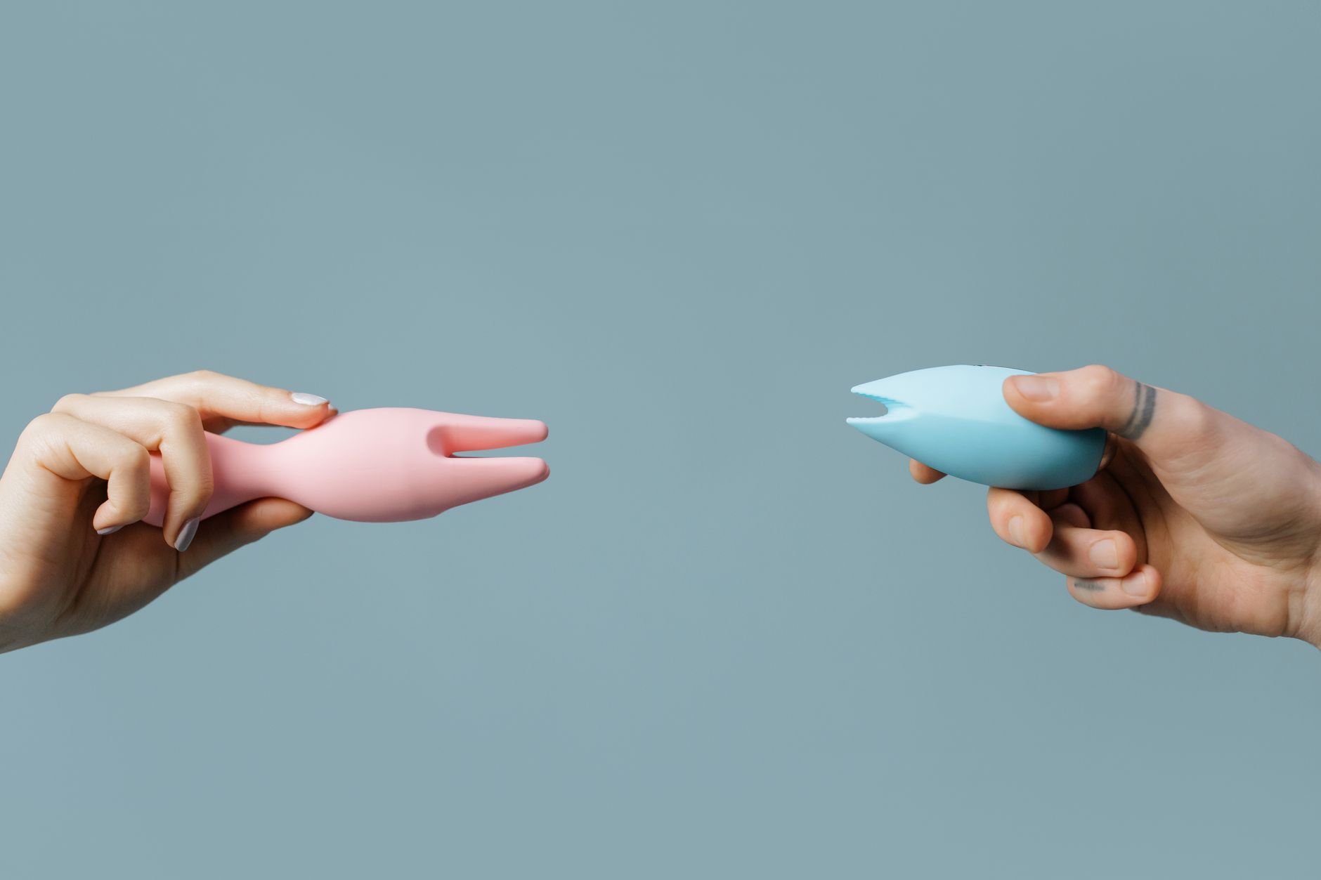 A hand holding an orange vibrator against a minimalistic purple backdrop