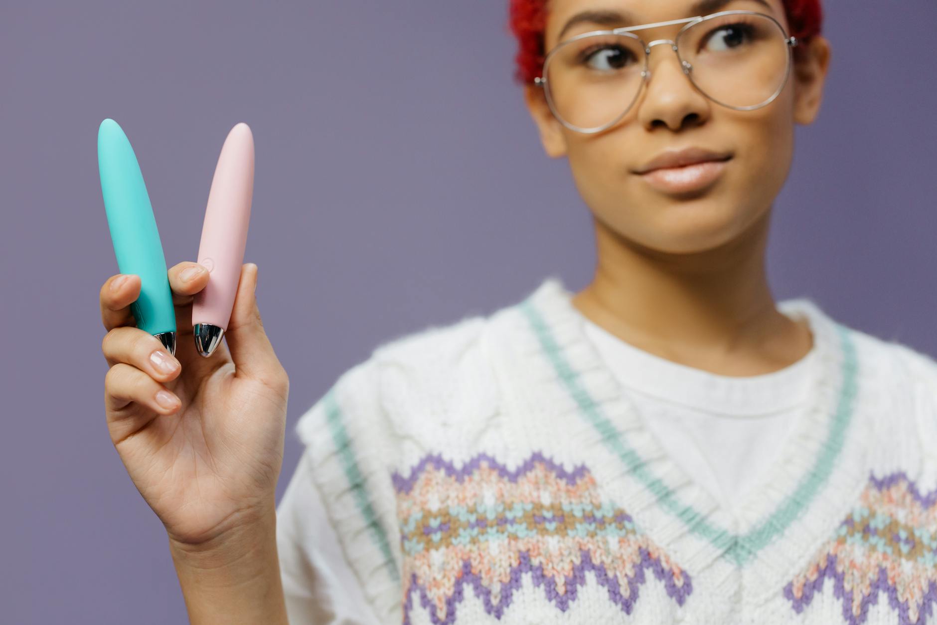 A young woman holding colorful vibrators, representing renewed connection to solo pleasure