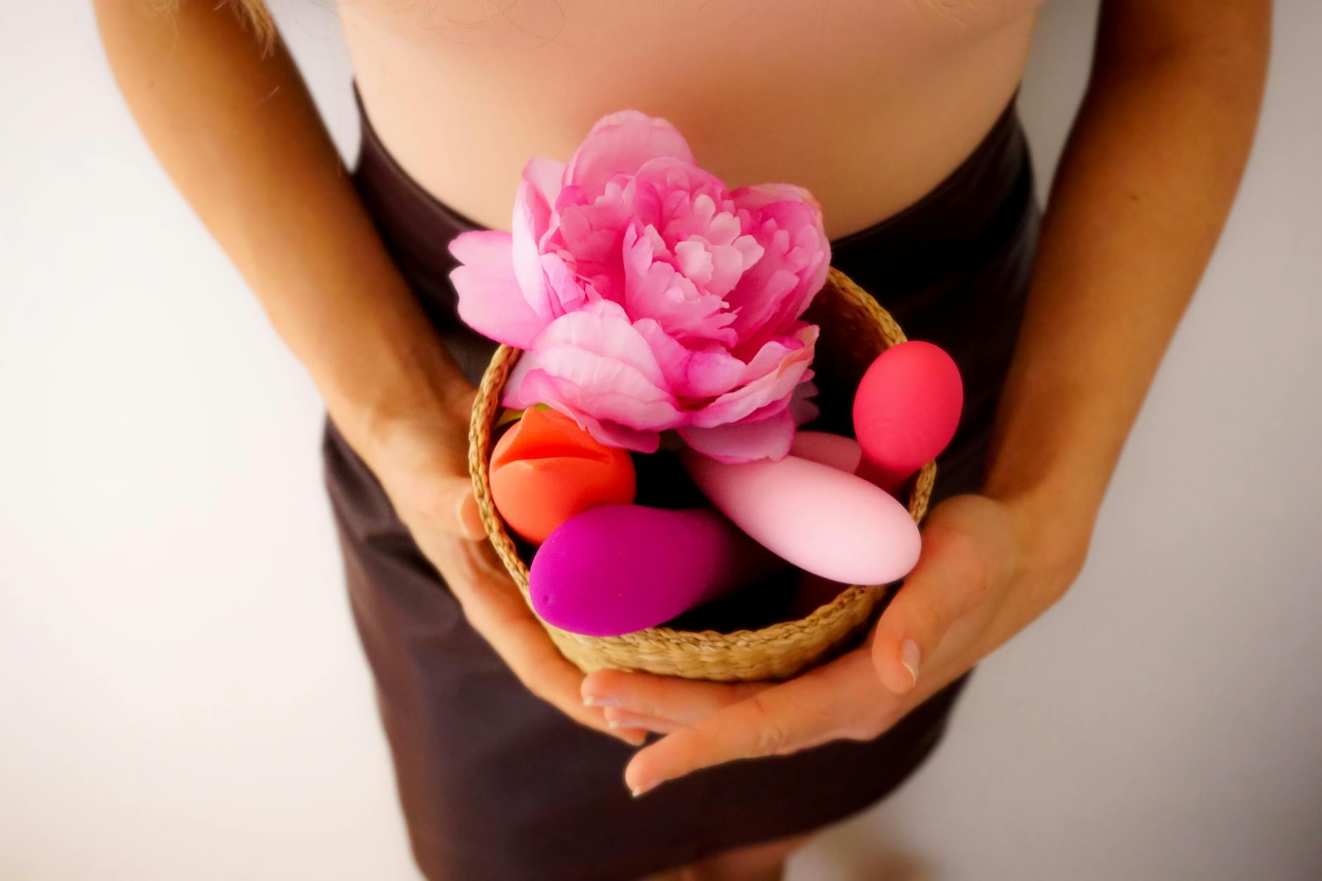 Person holding a pink vibrator with art books nearby, showing intimate self-care